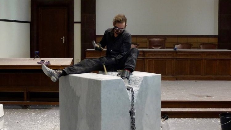 ศิลปินเบลเยียมล่ามโซ่ตัวเองไว้กับบล็อกคอนกรีตกลางศาล เพื่อที่จะแสดงศิลปะแนวเซอร์เรียล